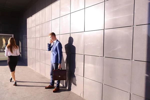 Handsome young man, businessman talking on phone passes by beaut