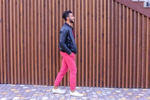 Atractivo joven árabe mira a su alrededor y pasea, sonríe y — Foto de Stock