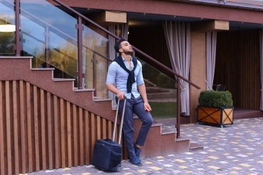 Çekici genç Arap adam elinde bavulla ayakta ve p