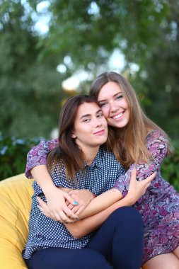 Sandalyede, yan yana oturan iki çekici kızlar smilin