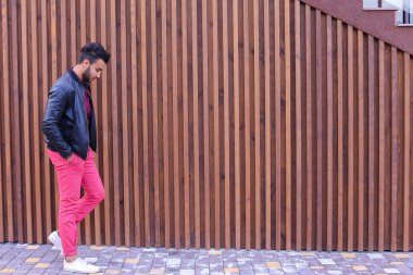 Çekici genç Arap adam etrafına bakıyor ve elini kolunu sallaya dönüyor, gülümser bir