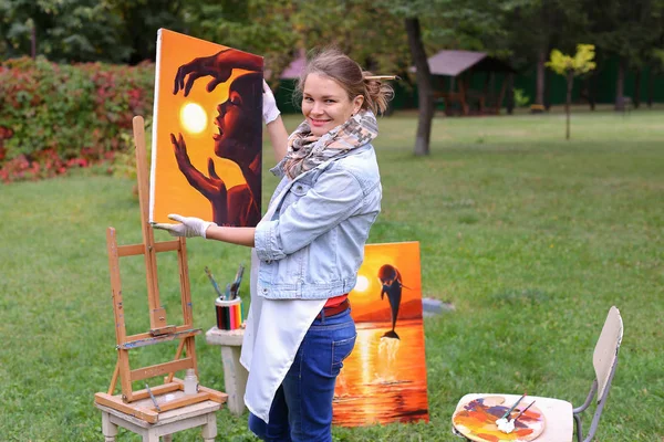 Umělec žena drží obraz a dívá se na to, Pózování na fotoaparátu — Stock fotografie