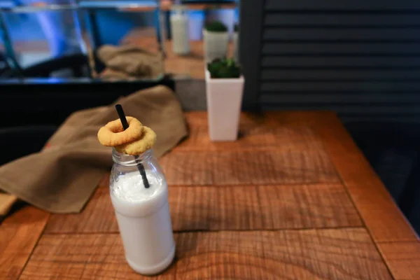 Kaca botol susu, bunga di vas dan rawa-rawa tirai di atas meja ag — Stok Foto