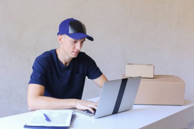 Postane bilgisayarda yazarak masada oturan kurye.