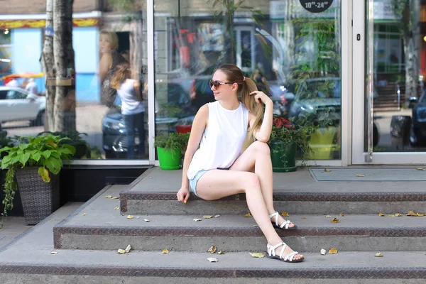 Mujer joven en el suelo en la calle mirando en cámara usando p —  Fotos de Stock