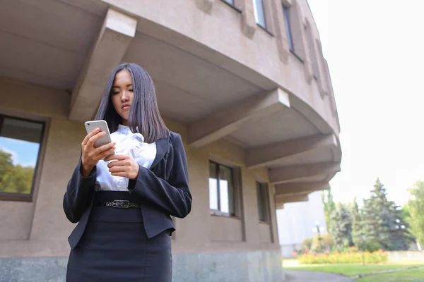 Όμορφη Νεαρά ασιατικές φοιτήτριας κρατώντας τηλέφωνο, χαμογελώντας και — Φωτογραφία Αρχείου