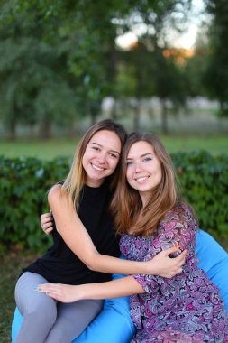 Sandalyede, yan yana oturan iki çekici kızlar smilin