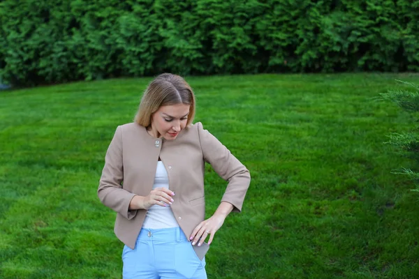 Nette Blondine steckt Smartphone in Hosentasche und steht — Stockfoto