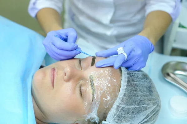 Female master of tattooing eyebrows holds special device on brow — Stock Photo, Image