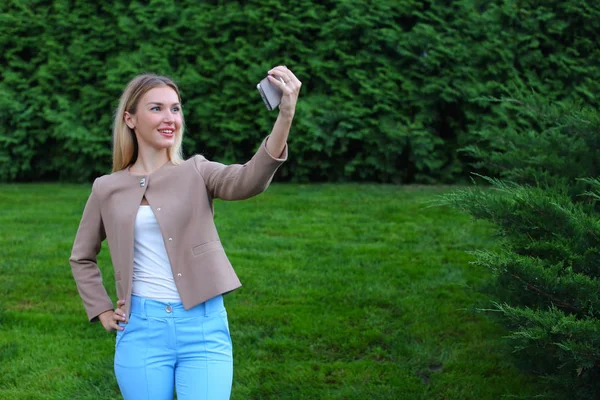 Junges nettes Mädchen hält Handy auf Armlänge und lenkt Lächeln — Stockfoto