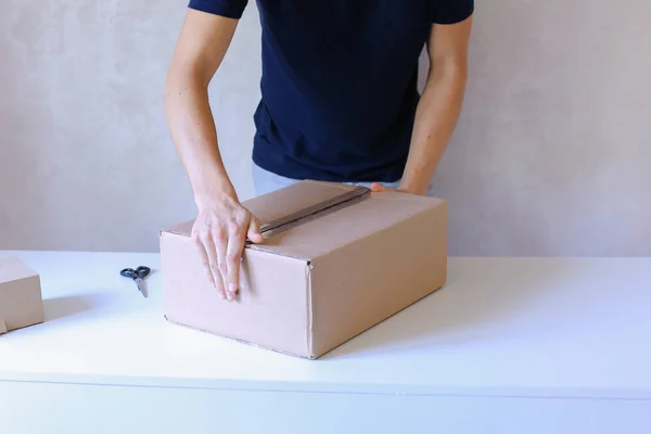 Young Man Glue Tape Box And Takes Parcel in Hands, Standing in P