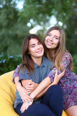 Sandalyede, yan yana oturan iki çekici kızlar smilin