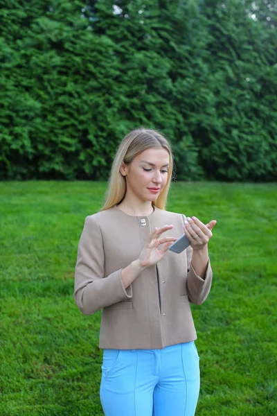 Linda chica sostiene el teléfono móvil y lo utiliza, sonríe y expresa e — Foto de Stock