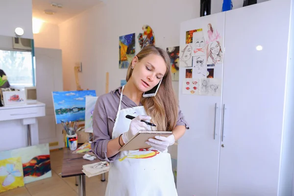 Artista chica sostiene cepillo en la mano y dibuja en la lona, recoge Ph —  Fotos de Stock