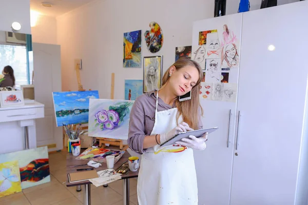 Chica artista sosteniendo el teléfono móvil y el uso, hablar, escribir pluma o —  Fotos de Stock