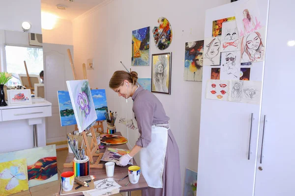 Όμορφη νεαρή ζωγράφος χρώματα εικόνα χρησιμοποιεί βούρτσες και λάδι, και — Φωτογραφία Αρχείου