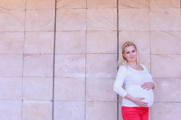 Bonito jovem grávida mulher delicadamente tocando barriga e posando em — Fotografia de Stock