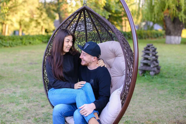 Niño y niña sentados juntos en silla suspendida, abrazando a cada uno o —  Fotos de Stock