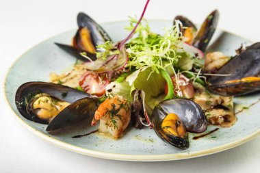 Beyaz arka plan üzerinde dairesel plaka üzerinde deniz ürünleri salatası.