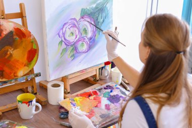 Kız sanatçı ile kamera geri oturur ve petrol resim çizer