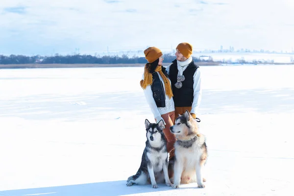 Retrato de pareja joven con perros sonriendo y abrazándose en invierno — Foto de Stock