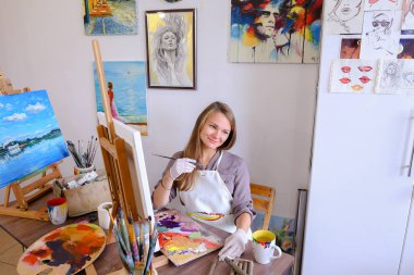 Kız şövale ve yazma boyama Stool'da oturur, fırça için kullanır