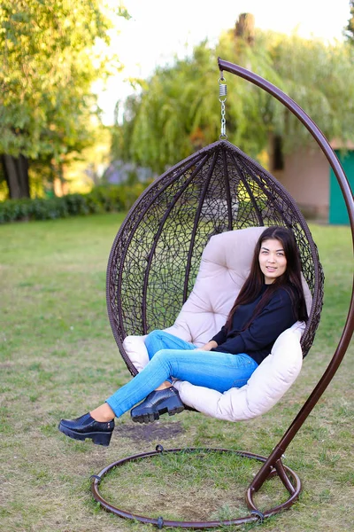 Pretty attractive woman sits comfortably in chair suspended by p