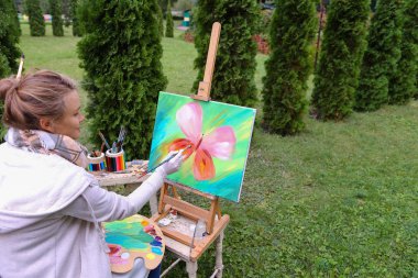 Profesyonel sanatçı kadın şövale b ile oturan resim yazıyor