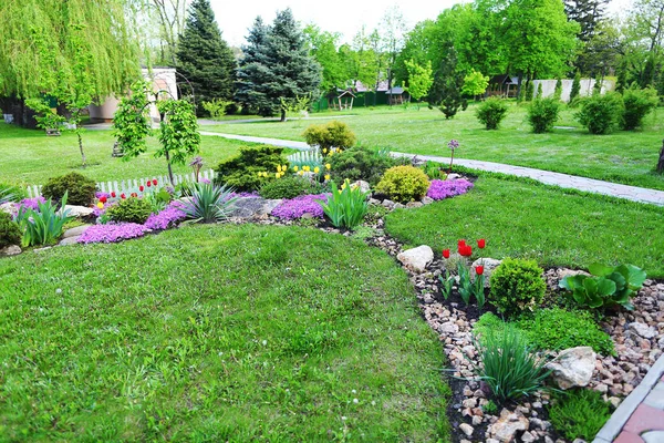 Landscaped area with green spaces, plants, flowers and trees in — Stock Photo, Image