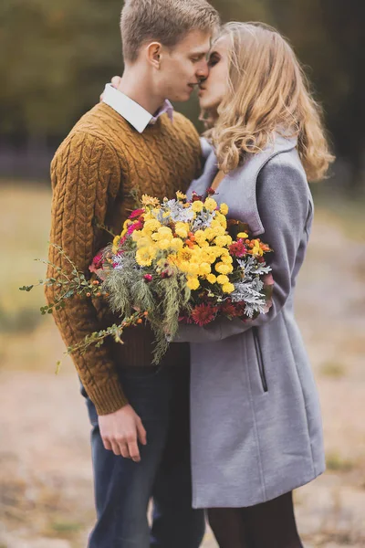 Çiçekler buket üzerinde odaklanın. Güzel genç çift sarılmak portresi — Stok fotoğraf