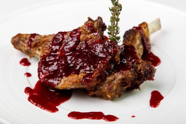 Beyaz arka plan üzerinde yuvarlak tabakta berry soslu kuzu.