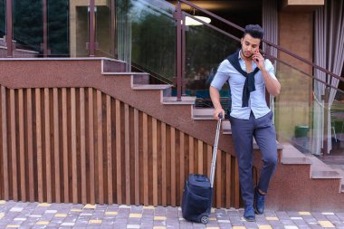 Çekici genç Arap adam elinde bavulla ayakta ve p