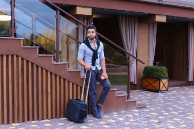 Çekici genç Arap adam elinde bavulla ayakta ve p