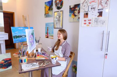 Kız şövale ve yazma boyama Stool'da oturur, fırça için kullanır