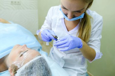 Kaşları dövme kadın efendi özel aygıt kaş üzerinde tutar.