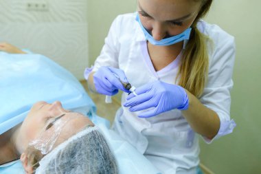 Kaşları dövme kadın efendi özel aygıt kaş üzerinde tutar.