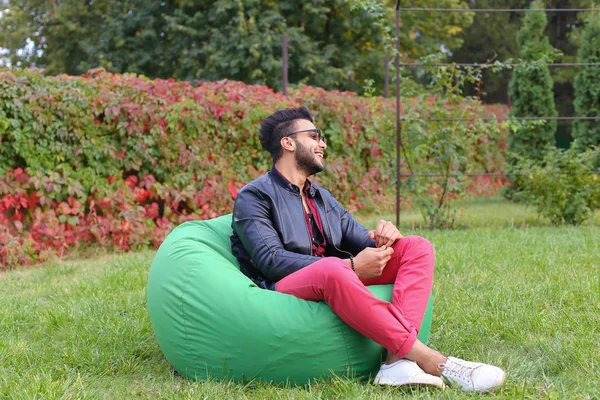 Arabe gars regarde musicalement à part et sourit, repos et assis dans — Photo