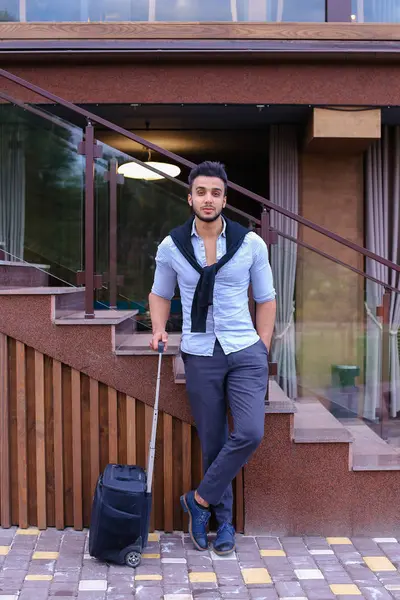 Atractivo joven árabe de pie con la maleta en la mano y p — Foto de Stock
