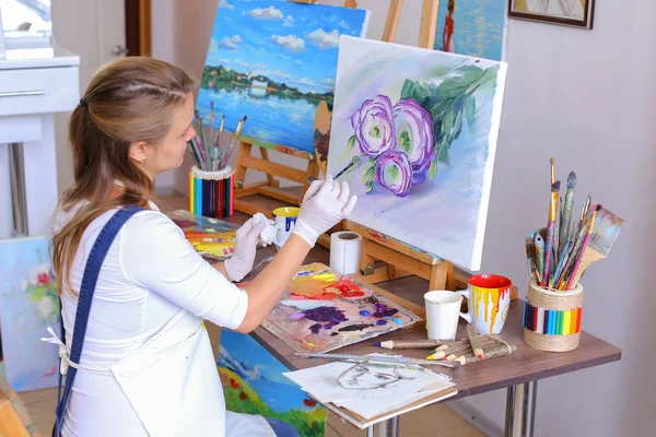 Menina artista senta-se com volta para a câmera e desenha imagem de óleo com — Fotografia de Stock
