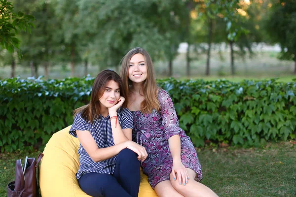 Két vonzó lány ül egymás mellett, széket, mosolygó — Stock Fotó