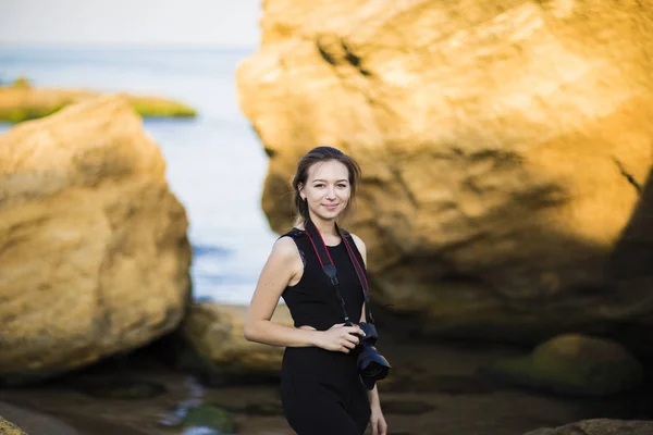 Güzel genç kadın turist fotoğrafçı denizde kamera ile portresi — Stok fotoğraf