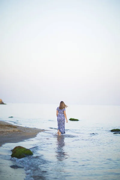 Portrait of beautiful young woman walks on coast of sea or ocean