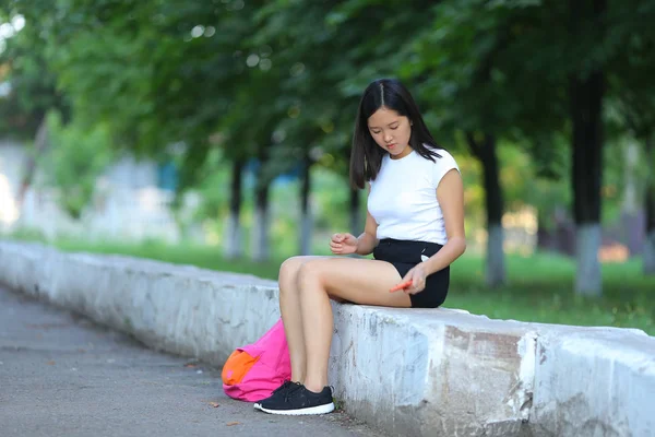 Młoda dziewczyna, siedząc i rozmawiając przez telefon w parku — Zdjęcie stockowe