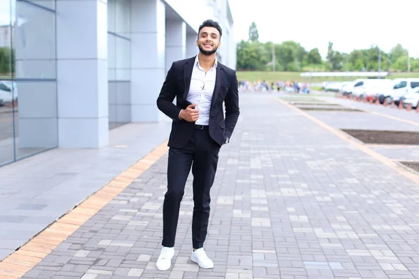 Arabic guy in business center stands smiling walking slow — Stock Photo, Image