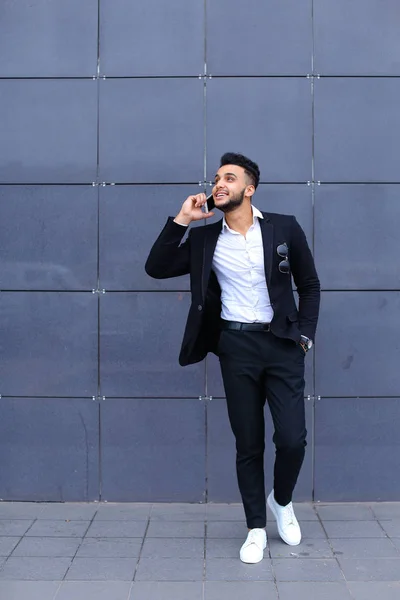 Hombre árabe guapo habla en el teléfono inteligente en el centro de negocios — Foto de Stock