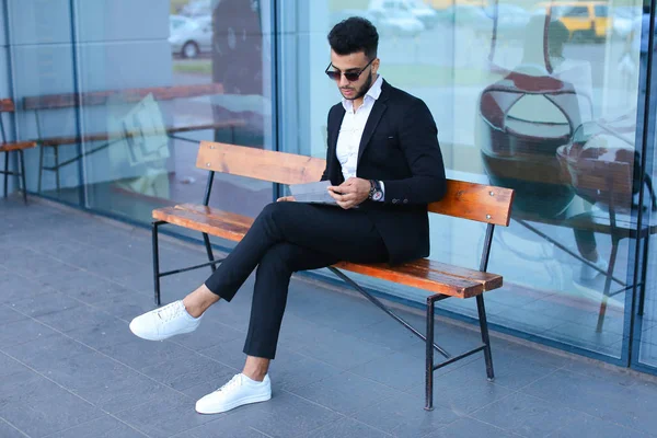 Homme en costume arabique met des lunettes de soleil avec tablette près des affaires — Photo