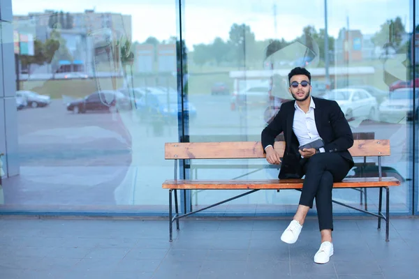 Hombre de traje árabe se pone gafas de sol con tableta cerca de negocios — Foto de Stock