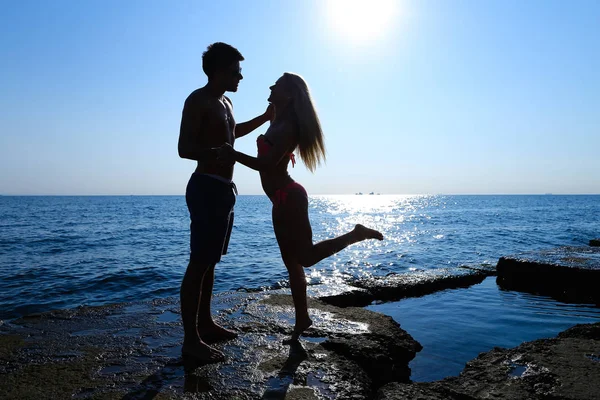Красиві стрункі молоді коханці стоять на скелі в морі, дивлячись в — стокове фото