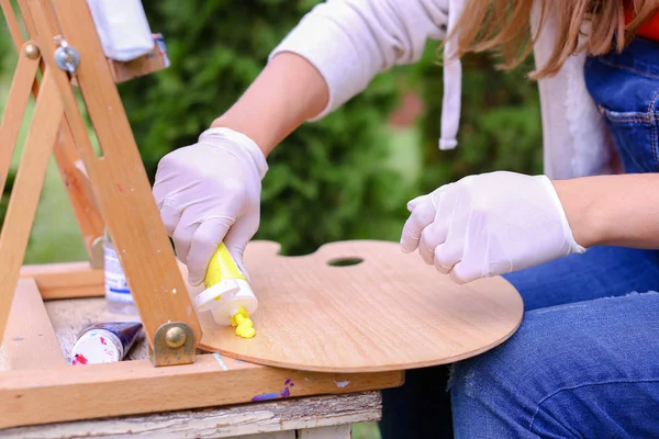 Vrouwen kunstenaars hand uit buizen olieverf op houten pale geperst — Stockfoto