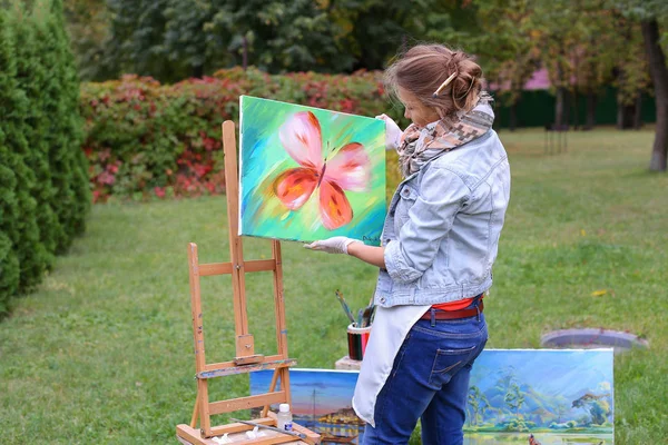 Artista mulher segura pintura e olha para ele, posando para câmera e — Fotografia de Stock